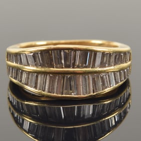 18K gold diamond ring. 2 channels of graduated baguette cut diamonds, largest approx. 3 x 1.8mm.