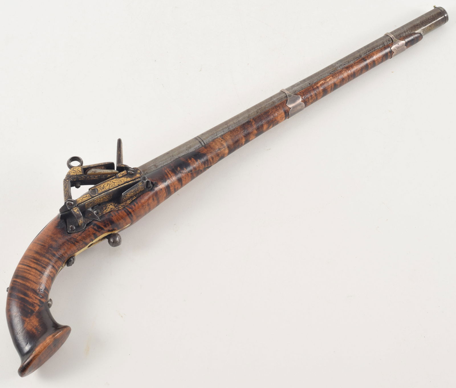 Fine Caucasian miquelet lock pistol, late 18th/early 19th century. Lock ornately engraved and: Fine Caucasian miquelet lock pistol, late 18th/early 19th century. Lock ornately engraved and retains traces of original gilding. Tiger-striped walnut stock fitted with engraved silver mounts.