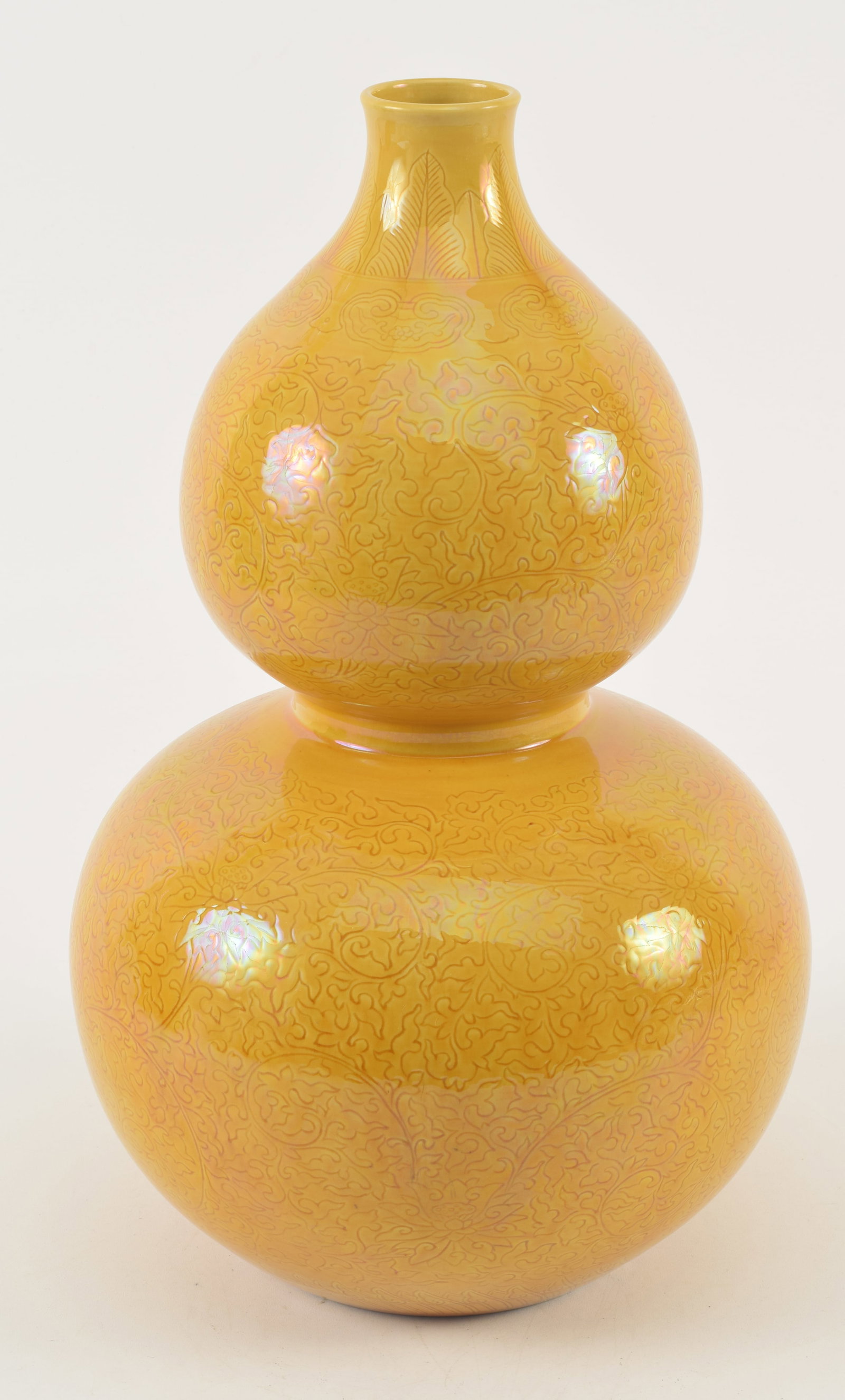 Porcelain vase. China. 19th/early 20th century. Double gourd form. Mustard yellow glaze. Surface: Porcelain vase. China. 19th/early 20th century. Double gourd form. Mustard yellow glaze. Surface engraved with stylized lotus scrolling. Chien Lung mark on the base. 15.5in.