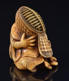 Netsuke of a child playing with a Kendo fencing mask. Japan. 19th century. Signed Minko. 1.5in.
