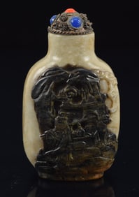 Jade snuff bottle. China. Ca. 1800. Black and chicken bone color. Finely carved with immortals in