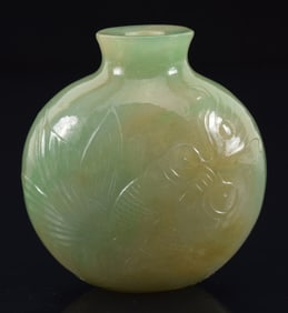 Jadeite snuff bottle. China. Ca. 1850. Surface carved in low relief with butterflies and flowers.