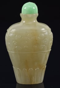 Celadon jade snuff bottle. China. Ca. 1850. Vasiform with the surface carved with archaic scrolling.