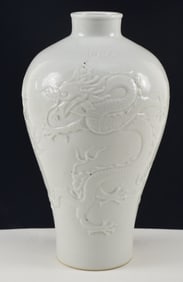 Porcelain vase. China. 20th century. White glaze. Molded decoration of dragons, clouds and pearls.