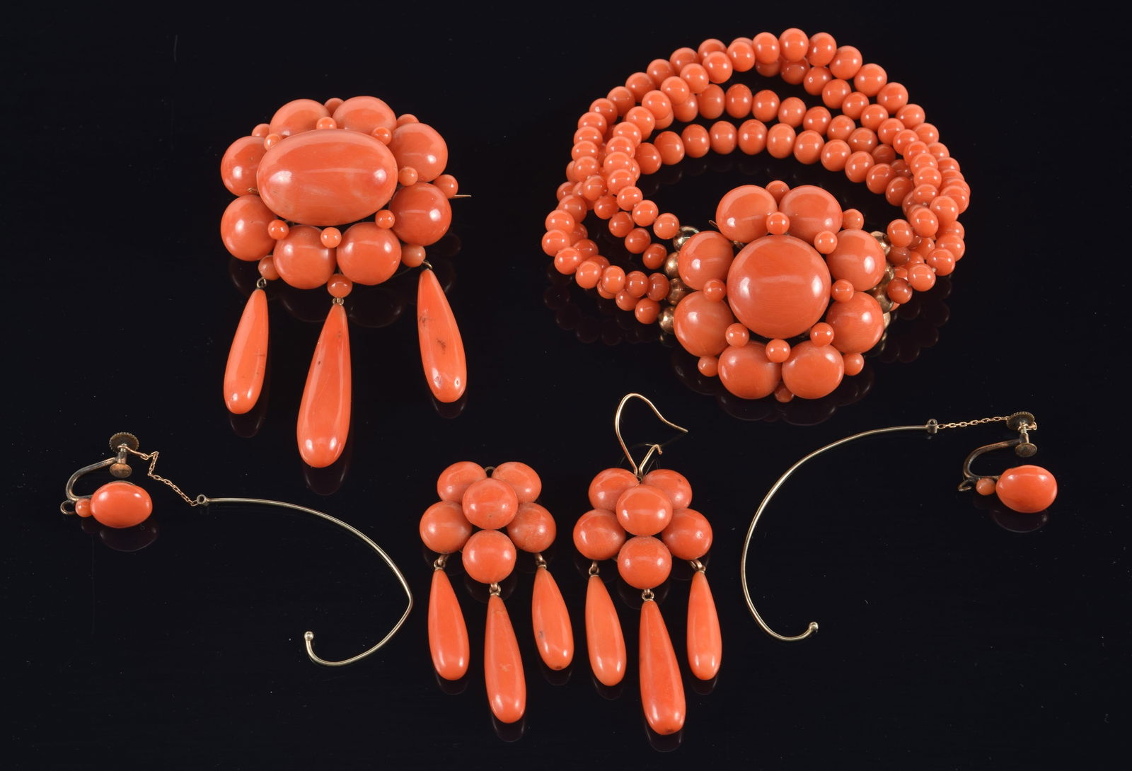 Antique 10K gold coral jewelry suite. To include: graduated bead multi-strand bracelet, screwback: Antique 10K gold coral jewelry suite. To include: graduated bead multi-strand bracelet, screwback earrings with long dangle attachments, and a brooch. Each with floral arrangements of variously sized