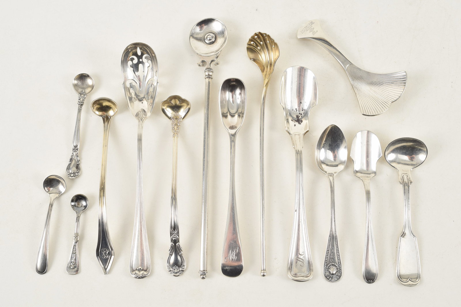 Collection of silver spoons and serving utensils. To include: 2 sterling cheese scoops, gilt shell (1 of 4)