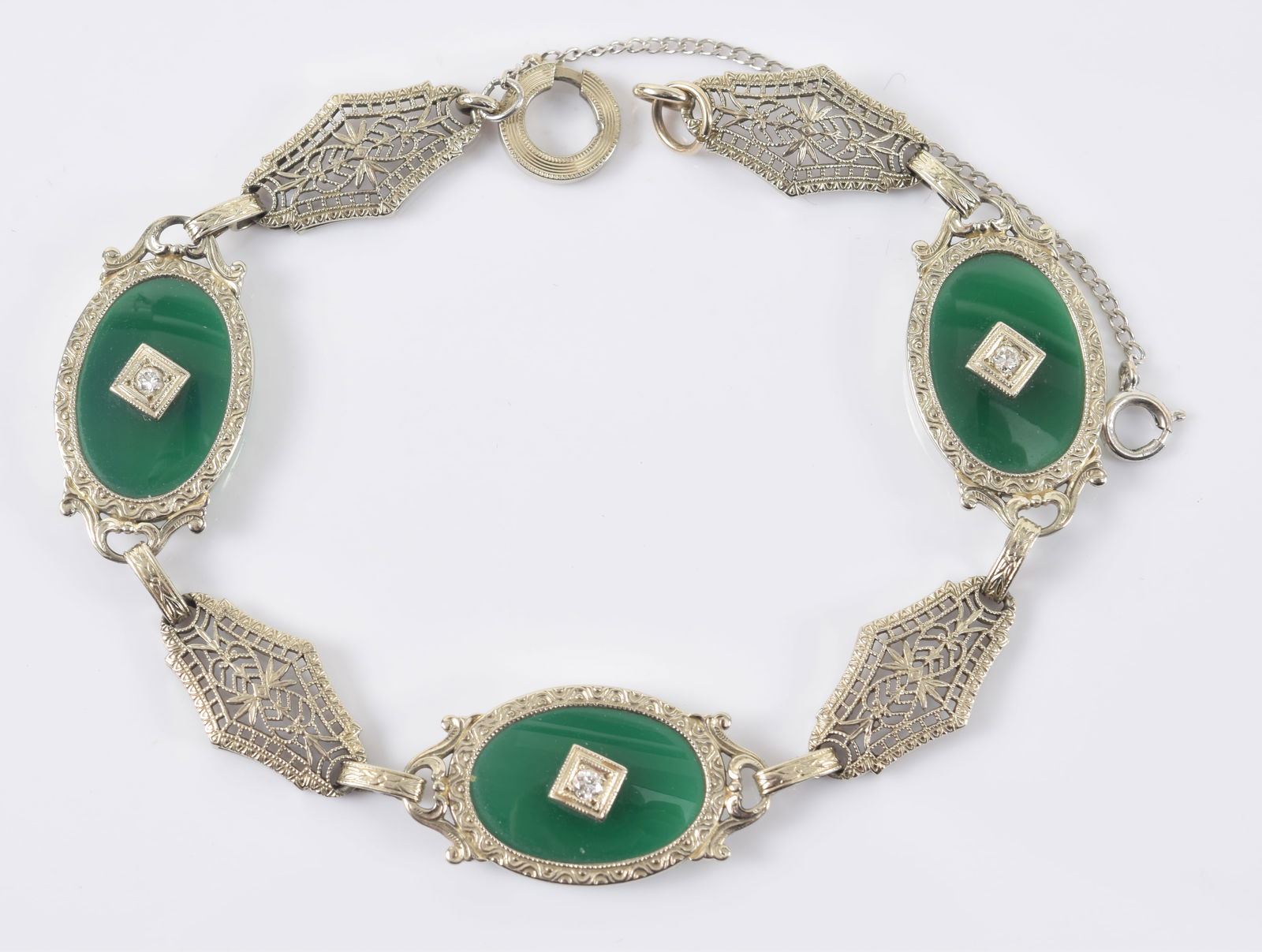 Edwardian 14K white gold chrysoprase and diamond bracelet. Oval stone mounted sections alternating: Edwardian 14K white gold chrysoprase and diamond bracelet. Oval stone mounted sections alternating with openwork filigree panels. Clasp marked 14K. 7in length. 9.8 grams.