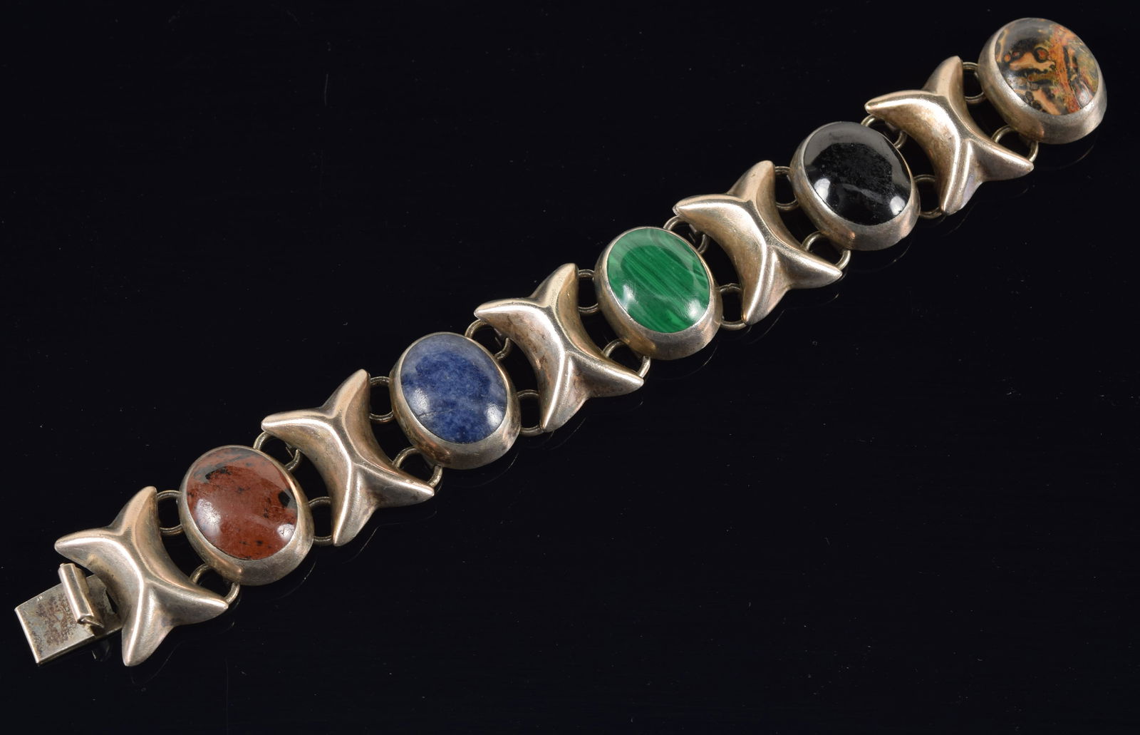 Mexican mid century sterling silver stone mounted bracelet. Large oval cabochons including: Mexican mid century sterling silver stone mounted bracelet. Large oval cabochons including Malachite, jasper?, and lapis. Stamped near clasp. Bracelet length: 7in. 2.2 ozt.