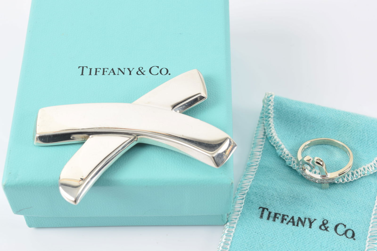 Paloma Picasso for Tiffany & Co. sterling silver jewelry pieces.1) Heart ring set with small: Paloma Picasso for Tiffany & Co. sterling silver jewelry pieces.1) Heart ring set with small diamonds. Marked inside band. Ring size 7.5. 2) X-form pin. Marked on reverse. 2.5in wide. 0.9 ozt.