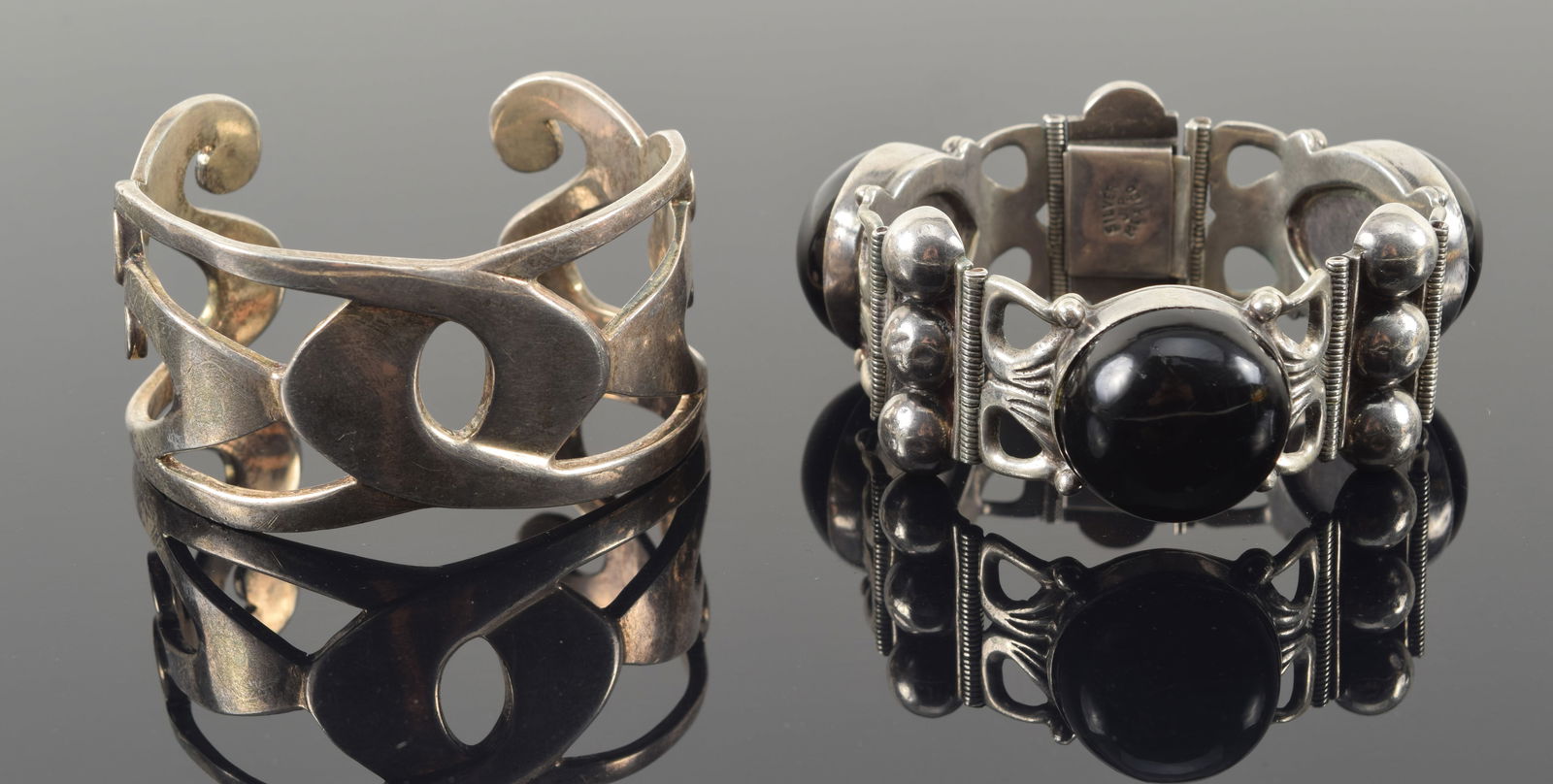 2 mid century modern sterling silver bracelets. 1) Cuff bracelet marked WM for Winterthur Museum.: 2 mid century modern sterling silver bracelets. 1) Cuff bracelet marked WM for Winterthur Museum. Small crack visible on reverse. 2) Mexican silver bracelet with large onyx cabochons. Signed J.P. 6.5i