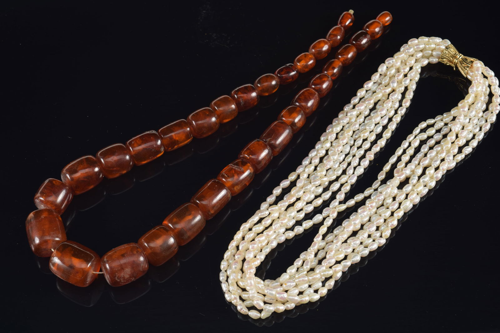 2 necklaces. 1) Large graduated barrel form amber bead necklace. Largest: 24mm length. 97 grams. 2) (1 of 7)