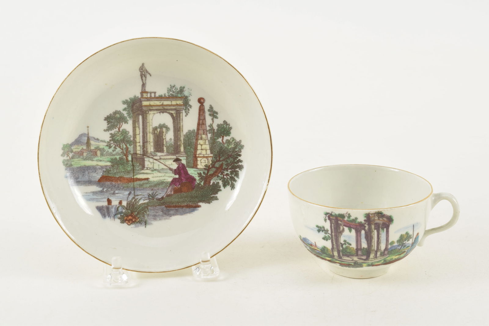 18th century Worcester porcelain cup and saucer with transfer classical ruins scene with a: 18th century Worcester porcelain cup and saucer with transfer classical ruins scene with a fisherman. Early crossed swords mark. 5.25in diameter. Cup 2in high. Provenance: From a Massachusetts collect