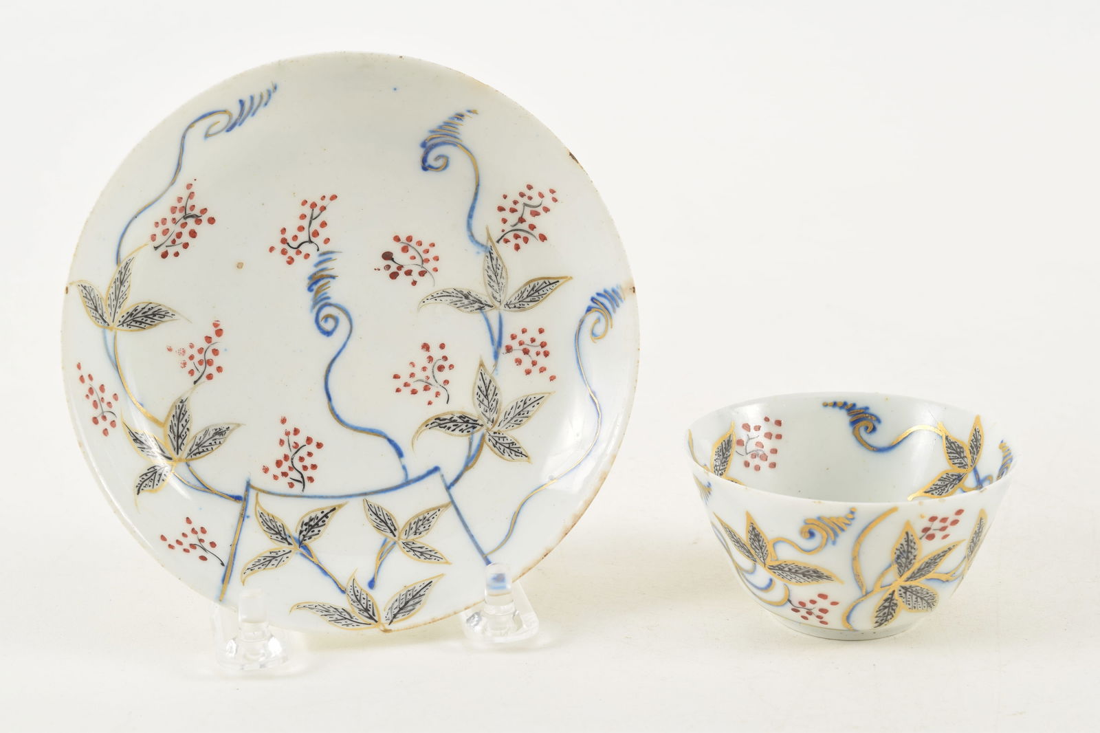 18th century porcelain cup and saucer with underglaze blue and floral decoration. Old label stating: 18th century porcelain cup and saucer with underglaze blue and floral decoration. Old label stating "Bow" porcelain. Saucer 4.75in diameter. Cup 1.5in high. Imperfections. Provenance: From a Massachus