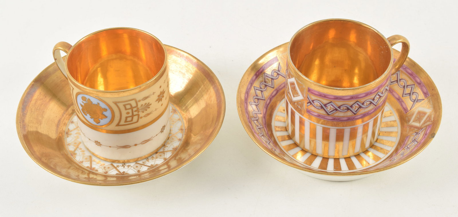 2 Empire gilt porcelain cups and saucers. Both with gilt ground and interiors. 1 with lavender: 2 Empire gilt porcelain cups and saucers. Both with gilt ground and interiors. 1 with lavender borders, the other cup with blue ground medallion and red "R" on base. Provenance: From a Massachusetts c