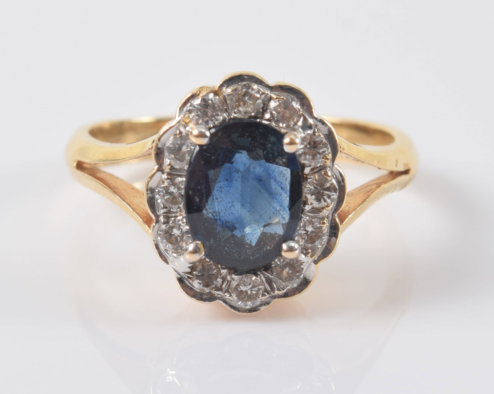 14K gold sapphire and diamond ring. Oval cut sapphire measures approx. 6.5 x 5.4mm. Surrounded by (1 of 5)