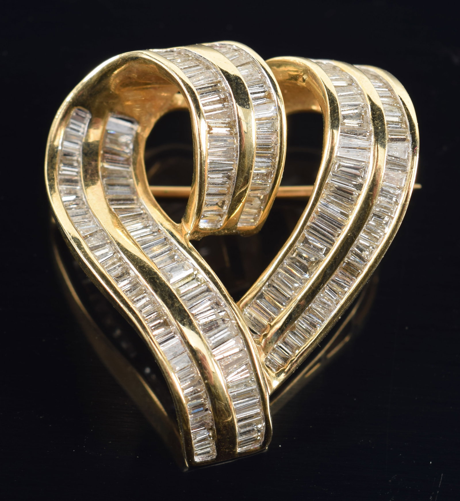 14K gold diamond heart form pin. 2 channels of tapered baguette cut diamonds of various sizes,: 14K gold diamond heart form pin. 2 channels of tapered baguette cut diamonds of various sizes, largest about 2 x 1.5mm. Marked 14K. 1.75in length. 12.2 grams.