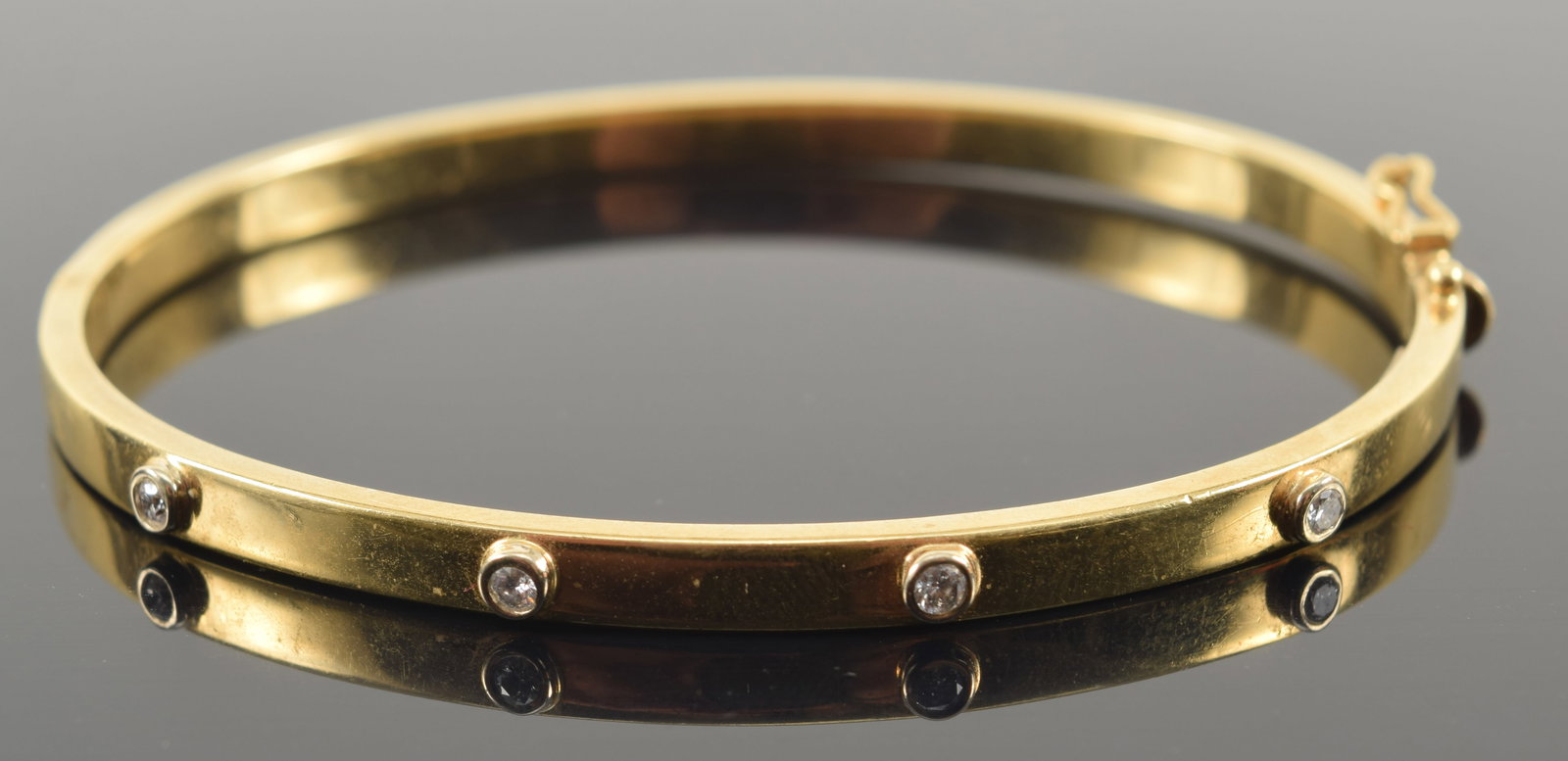 18K gold diamond bangle bracelet. 4 round cut diamonds, each about 2.5mm diameter. Marked near: 18K gold diamond bangle bracelet. 4 round cut diamonds, each about 2.5mm diameter. Marked near clasp. 2.5in wide. 7.6 grams.