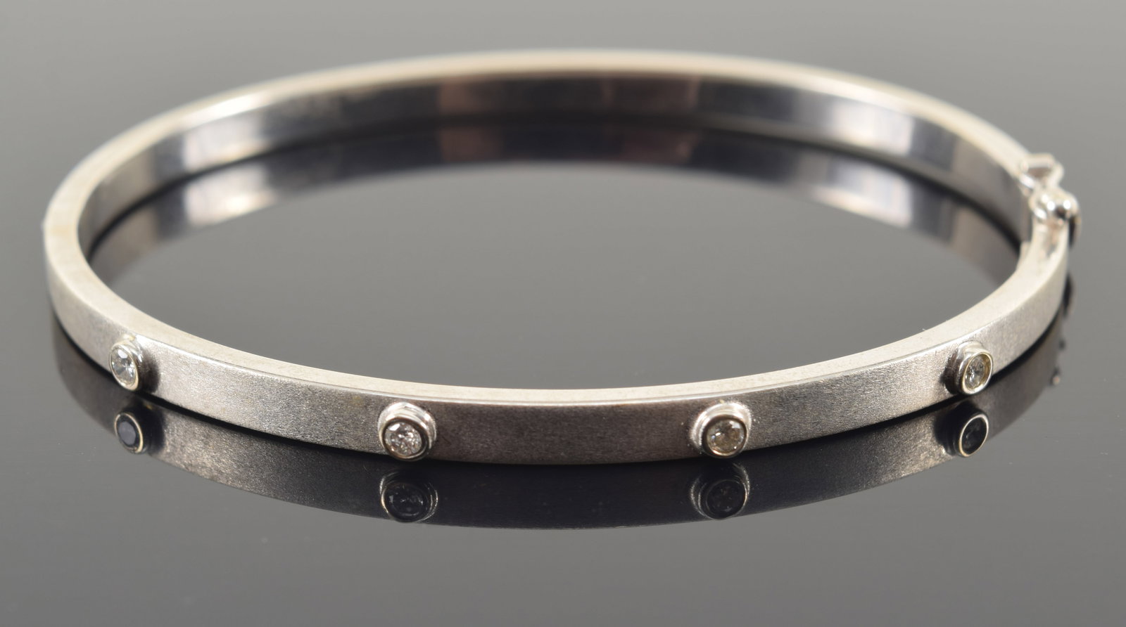 18K white gold diamond hinged bangle bracelet. Outer surface brushed finish, interior polished: 18K white gold diamond hinged bangle bracelet. Outer surface brushed finish, interior polished finish. 4 small round cut diamonds, each about 2.3mm diameter. Marked 18K Italy. Interior about 2.25in wi