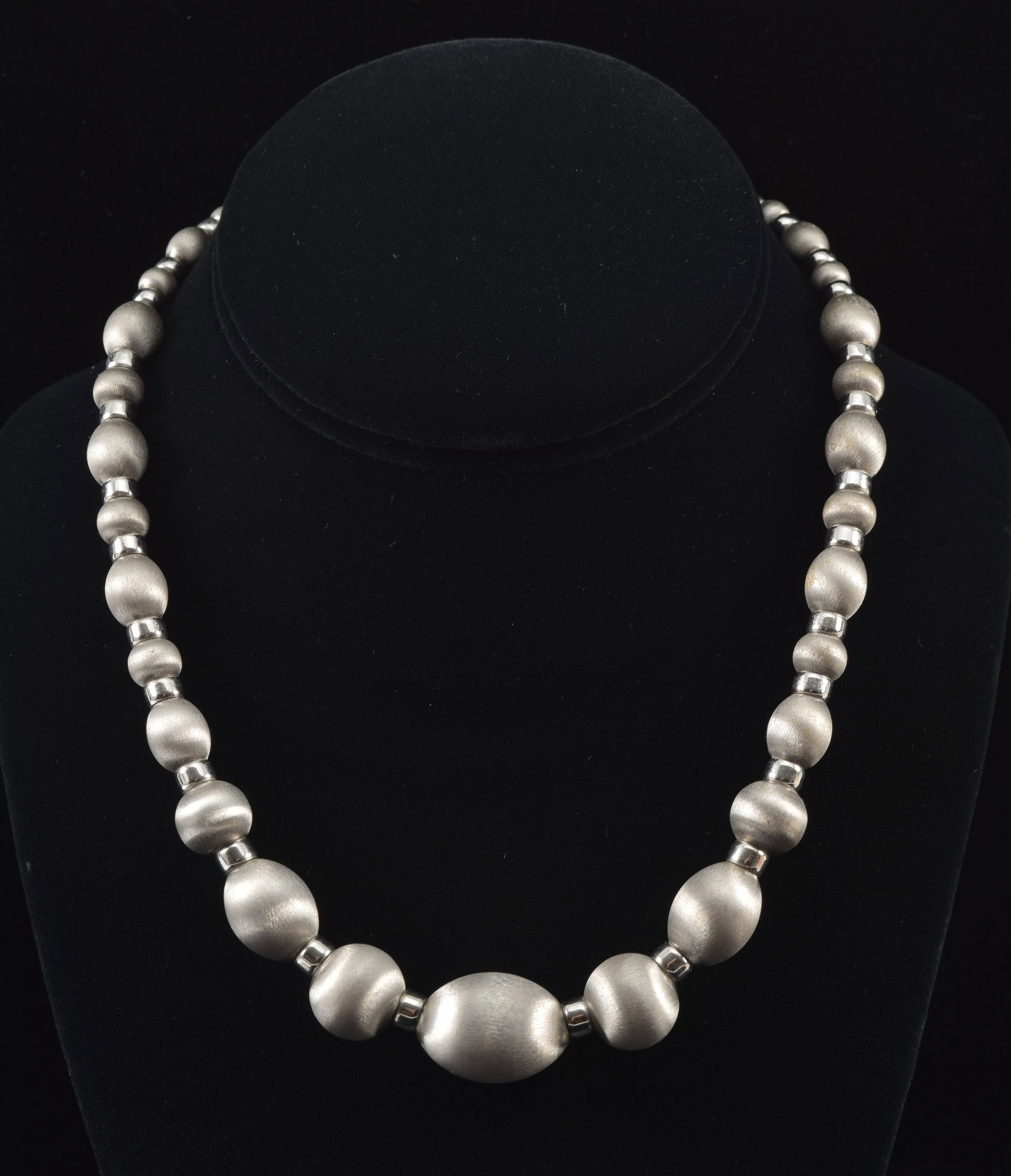 18K white gold graduated bead necklace with alternating pattern of spherical and oblong beads in: 18K white gold graduated bead necklace with alternating pattern of spherical and oblong beads in satin finish with polished spacers. Clasp marked 18K Italy. 17in length. 47.1 grams.