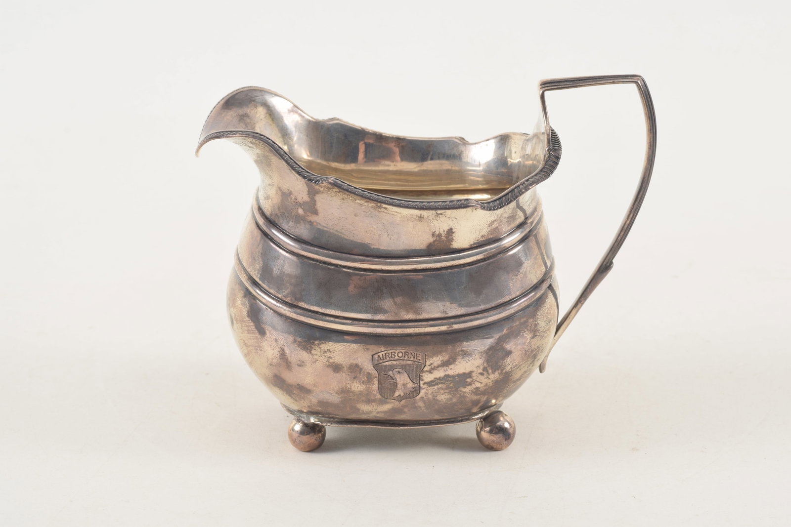[WWII Army Airborne] Georgian sterling silver creamer engraved with the United States Army Airborne: [WWII Army Airborne] Georgian sterling silver creamer engraved with the United States Army Airborne emblem and also bearing a gift inscription on the underside: "H.M. and A.M. from R.E.G. 1944". Sligh