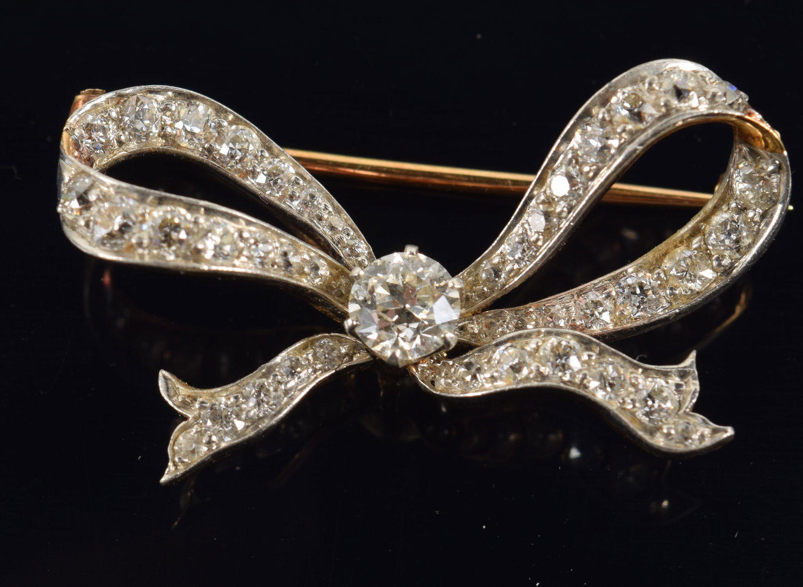 Tiffany & Co. 18K white and yellow gold diamond mounted bow pin, made to accept a lapel watch. White: Tiffany & Co. 18K white and yellow gold diamond mounted bow pin, made to accept a lapel watch. White gold front set with central diamond (4.9mm diameter) and 44 graduated round cut diamonds. Yellow go