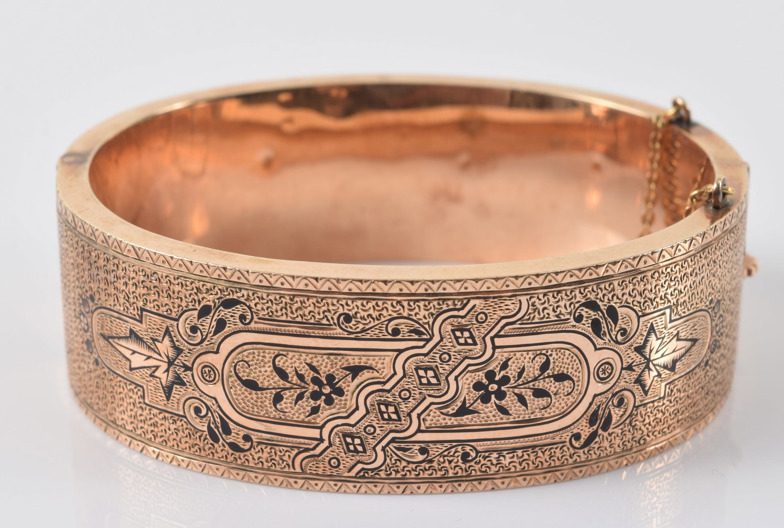14K gold Victorian aesthetic design bangle bracelet, ca. 1880. Black enamel accented floral and: 14K gold Victorian aesthetic design bangle bracelet, ca. 1880. Black enamel accented floral and geometric decoration. Several small pin-sized dents on interior. 2.5in wide. 31.2 grams.