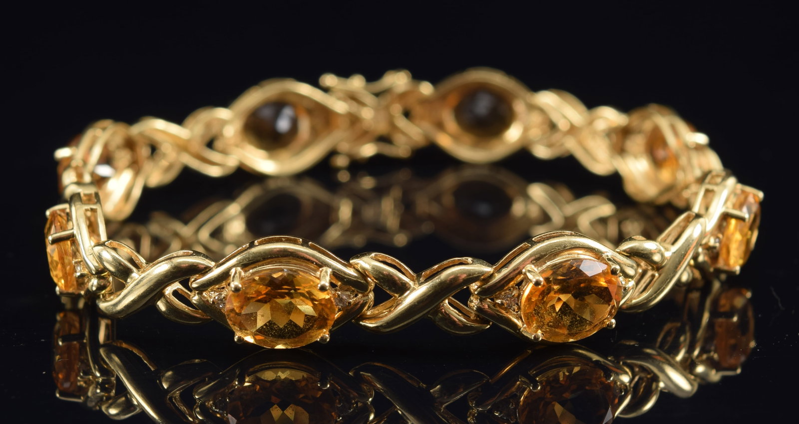 14K gold citrine and diamond mounted bracelet. Oval cut citrines each about 10 x 8mm. Each flanked: 14K gold citrine and diamond mounted bracelet. Oval cut citrines each about 10 x 8mm. Each flanked by two small round cut diamonds. Clasp marked 14K, 585 and WLC. Bracelet length: 8in. 17.3 grams.