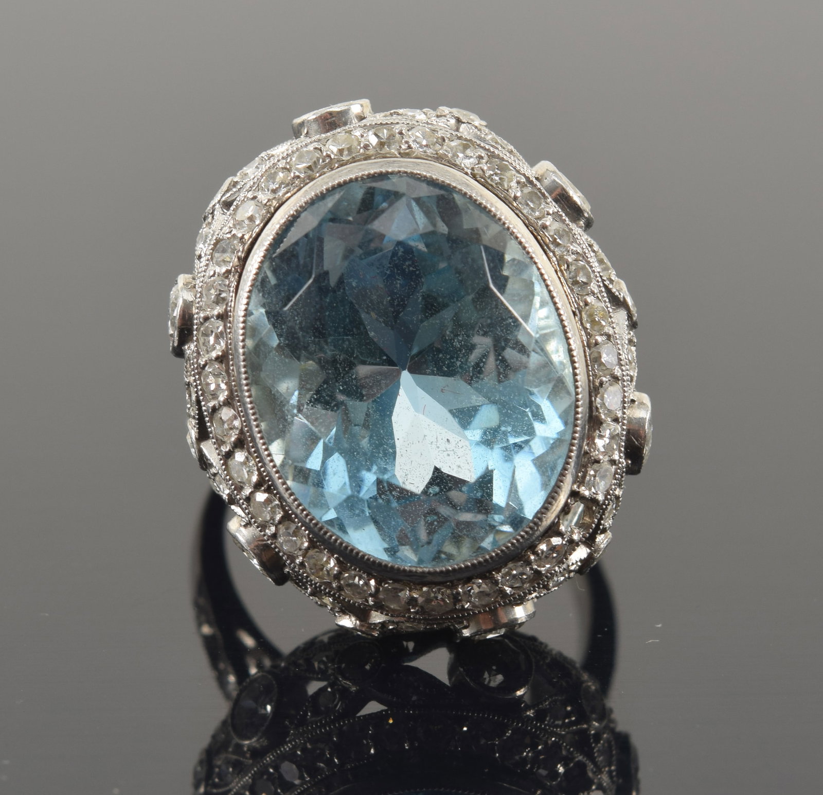 Platinum 8.0ct aquamarine and diamond ring. Oval center bezel cut aquamarine stone weighing: Platinum 8.0ct aquamarine and diamond ring. Oval center bezel cut aquamarine stone weighing approximately 8 carats (approx. 15 x 12mm). Stone of a deep blue color. Antique platinum and diamond setting