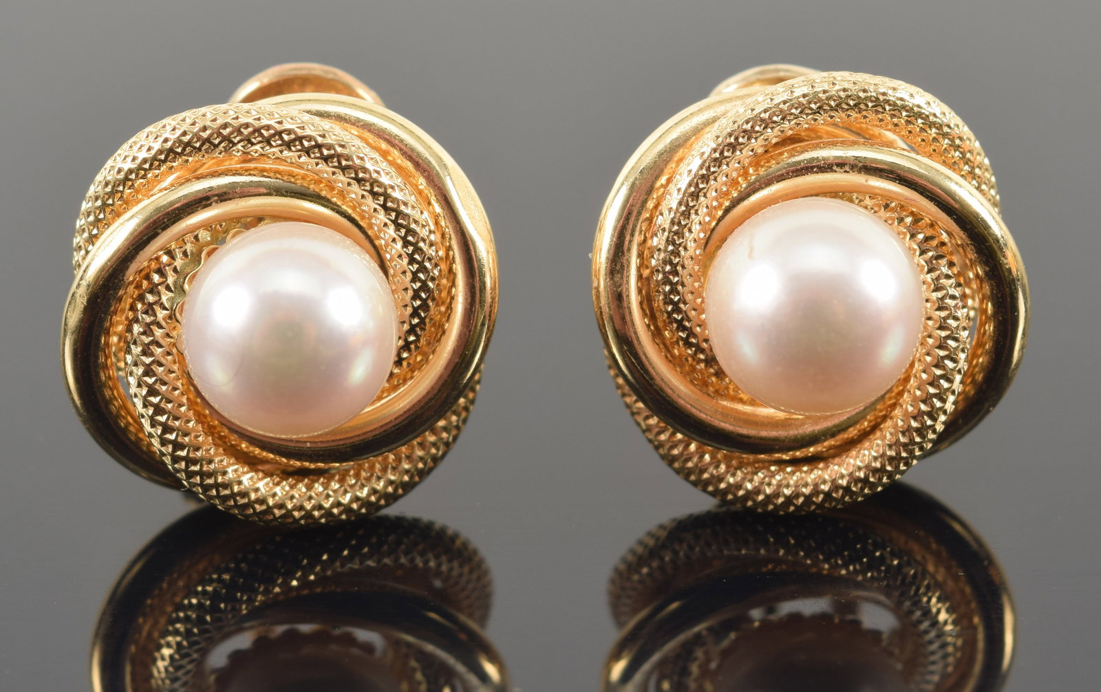 14K gold pearl mounted stud earrings. Coiled knot design. Pearls each about 7.8mm diameter. Overall:: 14K gold pearl mounted stud earrings. Coiled knot design. Pearls each about 7.8mm diameter. Overall: 0.75in diameter. 7.7 grams.