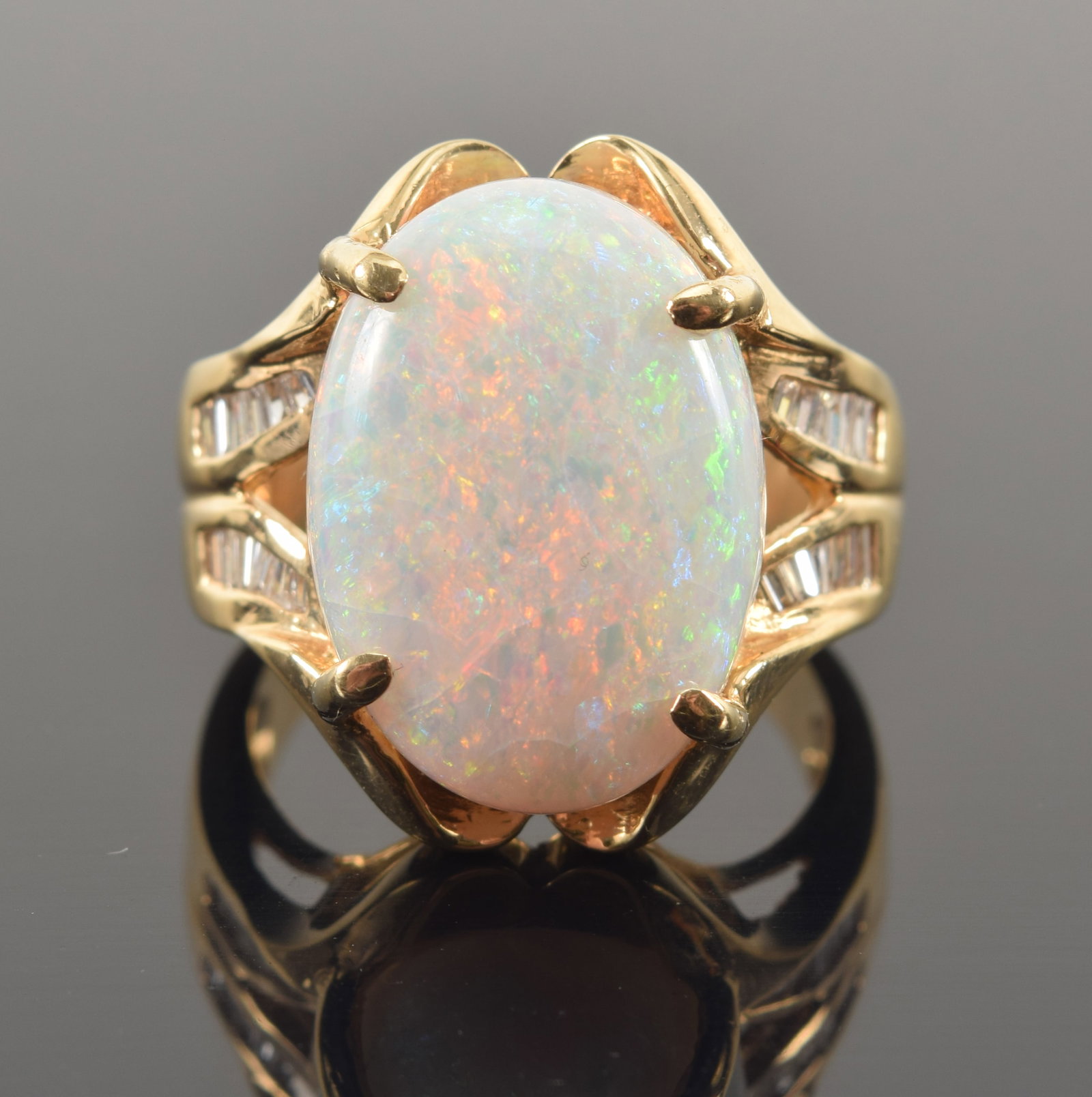 14K gold opal and diamond ring. Large oval stone measures 18.5 x 13.4mm. Flanked by 4 channels of: 14K gold opal and diamond ring. Large oval stone measures 18.5 x 13.4mm. Flanked by 4 channels of baguette diamonds. Unmarked but tests as 14K. Ring size 8.5. 10.4 grams.