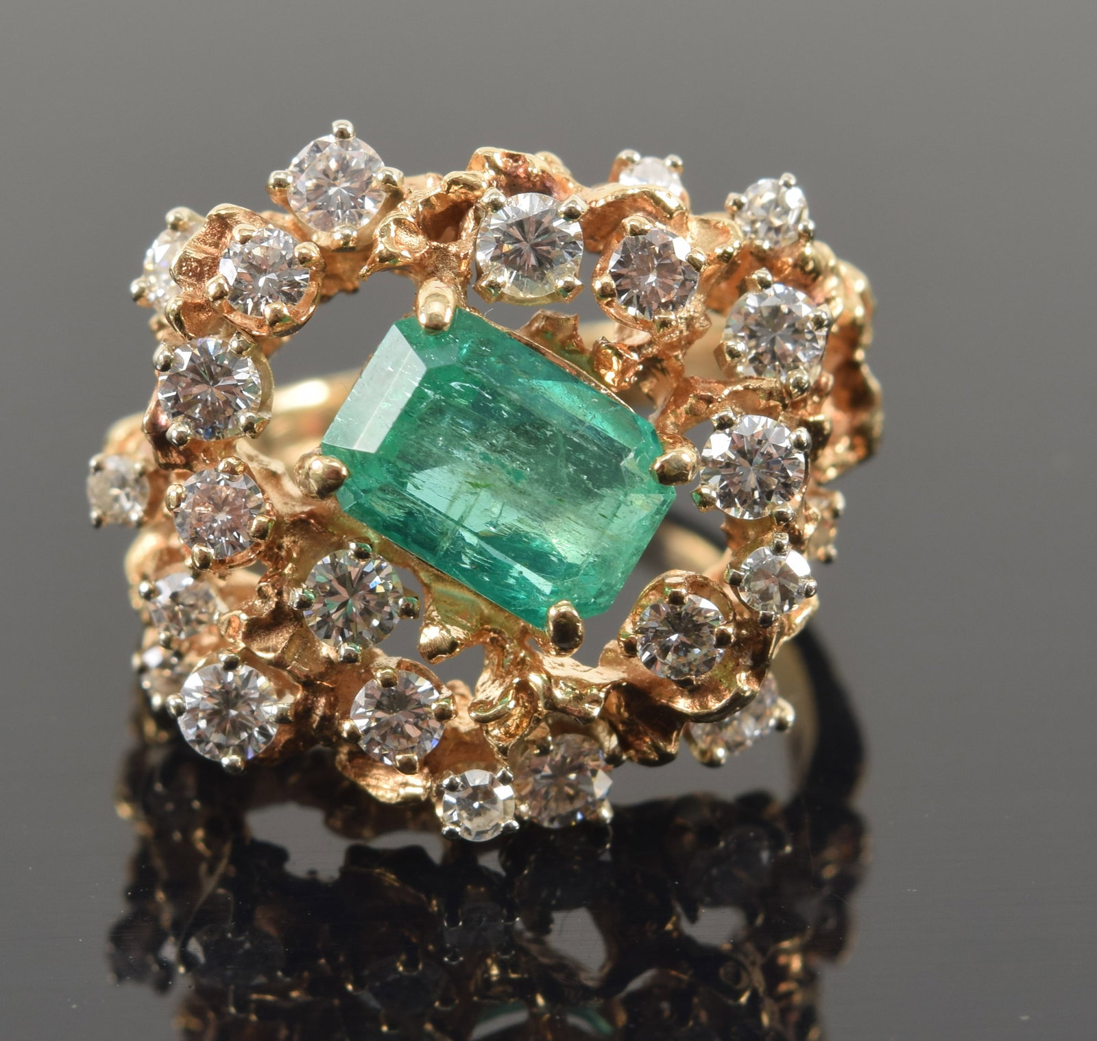 14K gold emerald and diamond ring. Central rectangular cut emerald weighing approx. 1.70cts.: 14K gold emerald and diamond ring. Central rectangular cut emerald weighing approx. 1.70cts. Surrounded by 23 prong set full cut diamonds, weighing approx. 0.90ctw. Naturalistic openwork setting. Stam