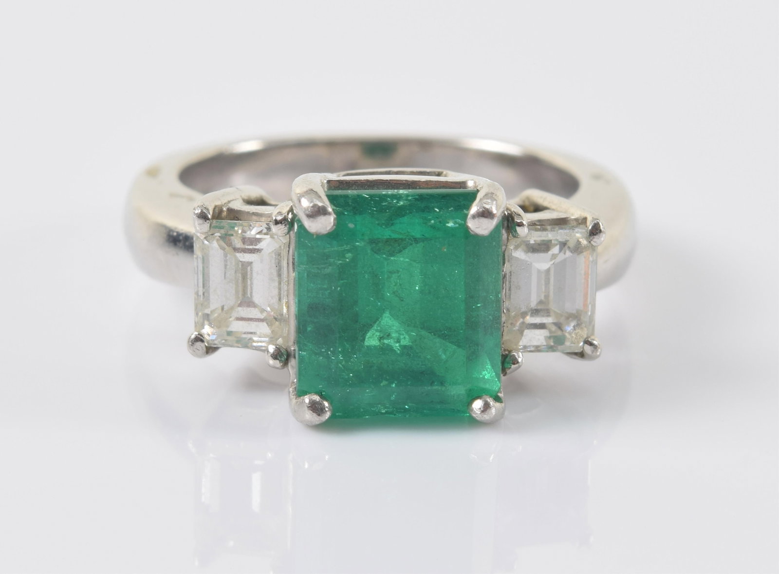 Platinum 3.02CT emerald and diamond ring. Emerald cut emerald stone measuring approx. 9.04 x 8.03 x: Platinum 3.02CT emerald and diamond ring. Emerald cut emerald stone measuring approx. 9.04 x 8.03 x 6.33mm and weighing 3.02cts. Medium dark green in color. Clarity enhanced. Flanked by 2 emerald cut 