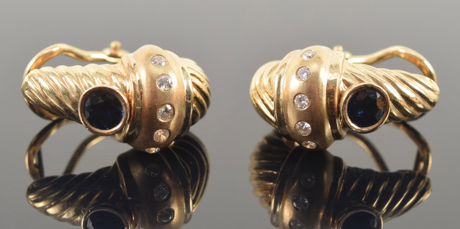 14K gold sapphire and diamond cable earrings. Tapered cable design with raised band of small round: 14K gold sapphire and diamond cable earrings. Tapered cable design with raised band of small round cut diamonds. Sapphires approx. 4.3mm diameter. Marked 14K. 7/8in length. 14 grams.