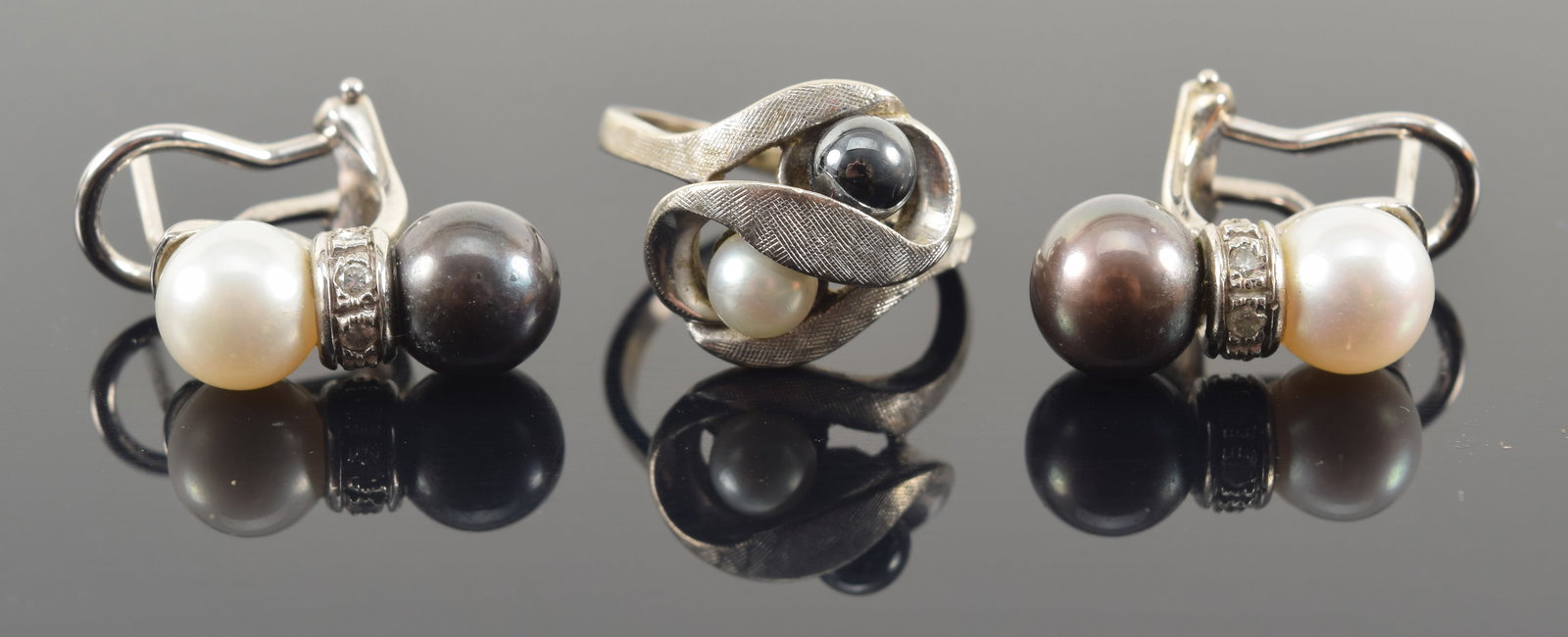 White gold black and white pearl jewelry. To include: 1) 14K earrings with 2 pearls and band of: White gold black and white pearl jewelry. To include: 1) 14K earrings with 2 pearls and band of diamonds. Marked JCR and 14K. 8.5 grams. 2) 10K ring with small pearls. Marked 10K. Ring size 5. 4.1 gra