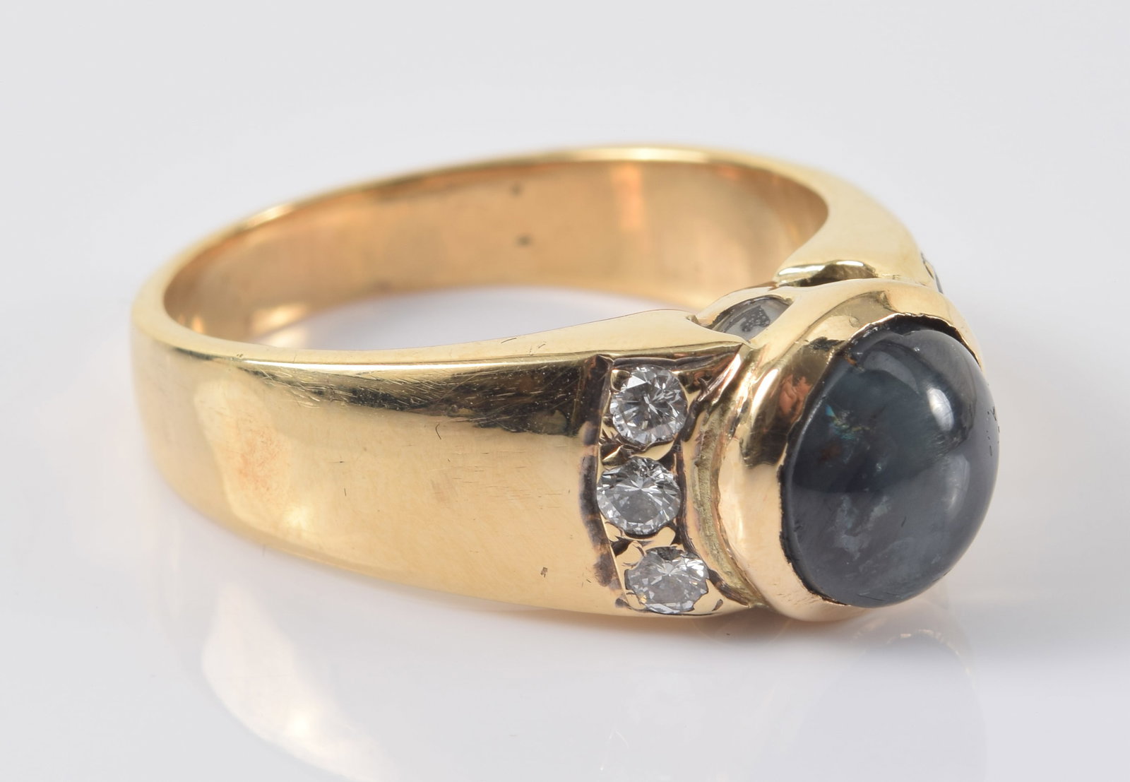 14K gold cat's eye chrysoberyl and diamond mounted ring. Cat's eye of a deep green/purplish red: 14K gold cat's eye chrysoberyl and diamond mounted ring. Cat's eye of a deep green/purplish red color. Measures approx. 8.8 x 8.1 x 8.5mm. Flanked by 3 round cut diamonds on each side. Stamped 14K and