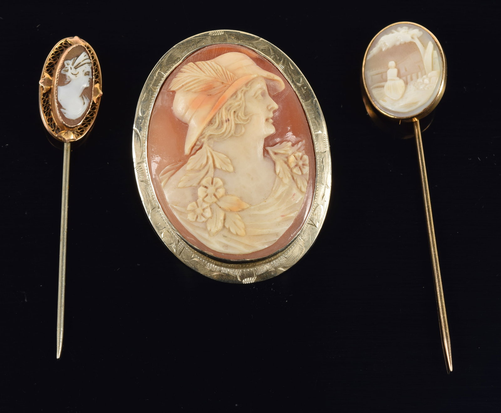 Lot of 3 gold cameos. 1) 14K gold cameo pin with profile bust of a woman wearing a feathered hat.: Lot of 3 gold cameos. 1) 14K gold cameo pin with profile bust of a woman wearing a feathered hat. Stamped 14K. 1.75in. 2) 2 gold cameo stick pins.