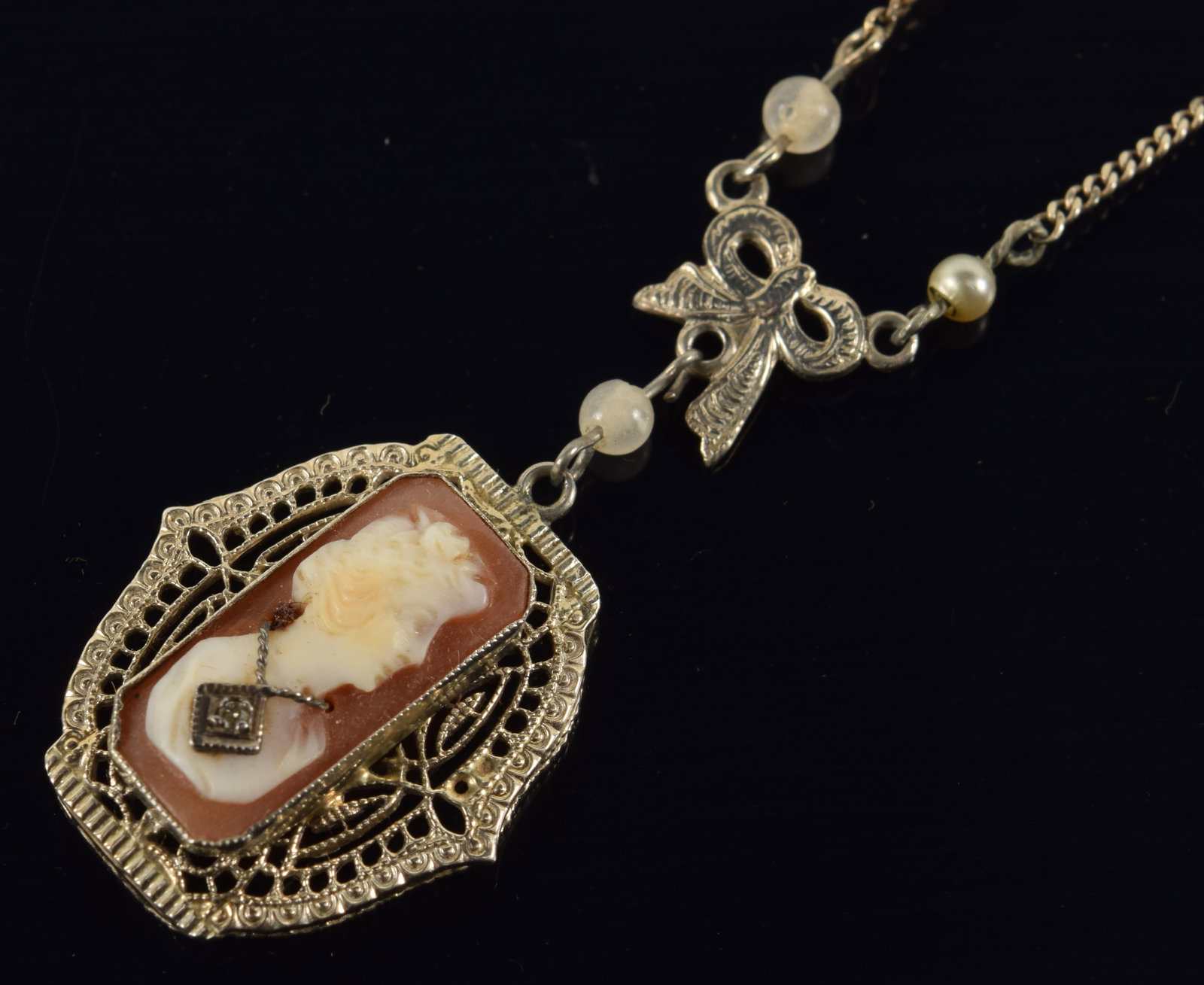 14K white gold cameo pendant necklace. Reticulated setting with rectangular cameo bust of a woman: 14K white gold cameo pendant necklace. Reticulated setting with rectangular cameo bust of a woman wearing diamond set necklace. Pendant and clasp marked 14K. 15.5in chain length. 3.5 grams.