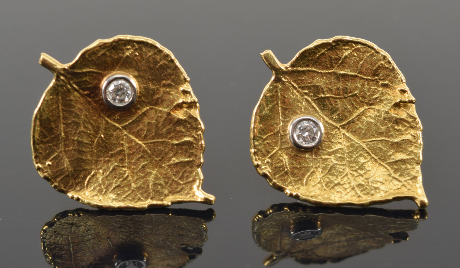 Aaron Henry 19K gold and platinum diamond mounted leaf form earrings. Round cur diamonds each about: Aaron Henry 19K gold and platinum diamond mounted leaf form earrings. Round cur diamonds each about 2.5mm diameter. Textured leaf surface. Stamped on reverse. 0.75in wide, each. 5.2 grams.