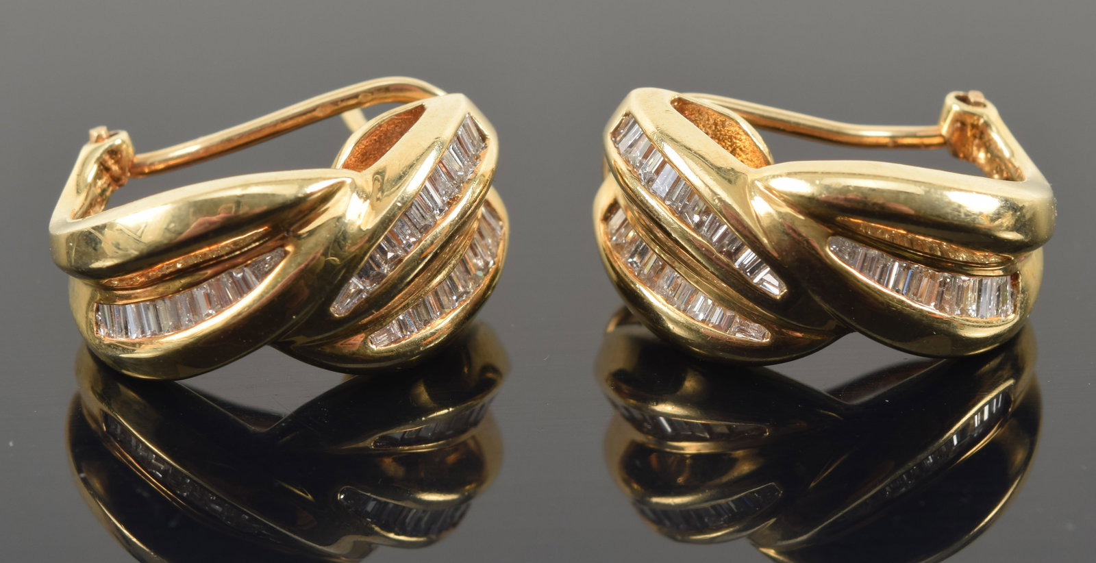 14K gold half hoop design diamond mounted earrings. Each with 3 channels of graduated baguette cut: 14K gold half hoop design diamond mounted earrings. Each with 3 channels of graduated baguette cut diamonds. Stamped 14K, 585, and maker's mark. 0.75in length. 8.5 grams.