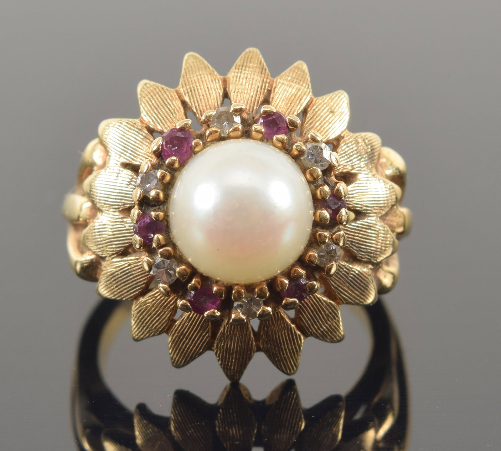 Vintage 14K gold pearl, diamond, and ruby sunflower ring. Central pearl (7.6mm diameter) with halo: Vintage 14K gold pearl, diamond, and ruby sunflower ring. Central pearl (7.6mm diameter) with halo of small diamonds and rubies and a ring of sunflower petals. Pierced shank. Marked 14K and TCJI. Ring