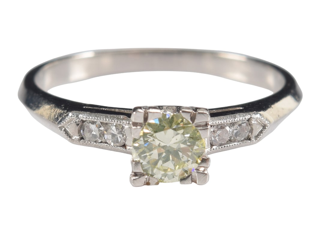 Vintage platinum yellow diamond ring. Central diamond of a pale yellow color and measuring 4.5mm: Vintage platinum yellow diamond ring. Central diamond of a pale yellow color and measuring 4.5mm diameter. Flanked by 2 small round cut diamonds on each side. Marked platinum. Ring size 6.5. 3.1 grams
