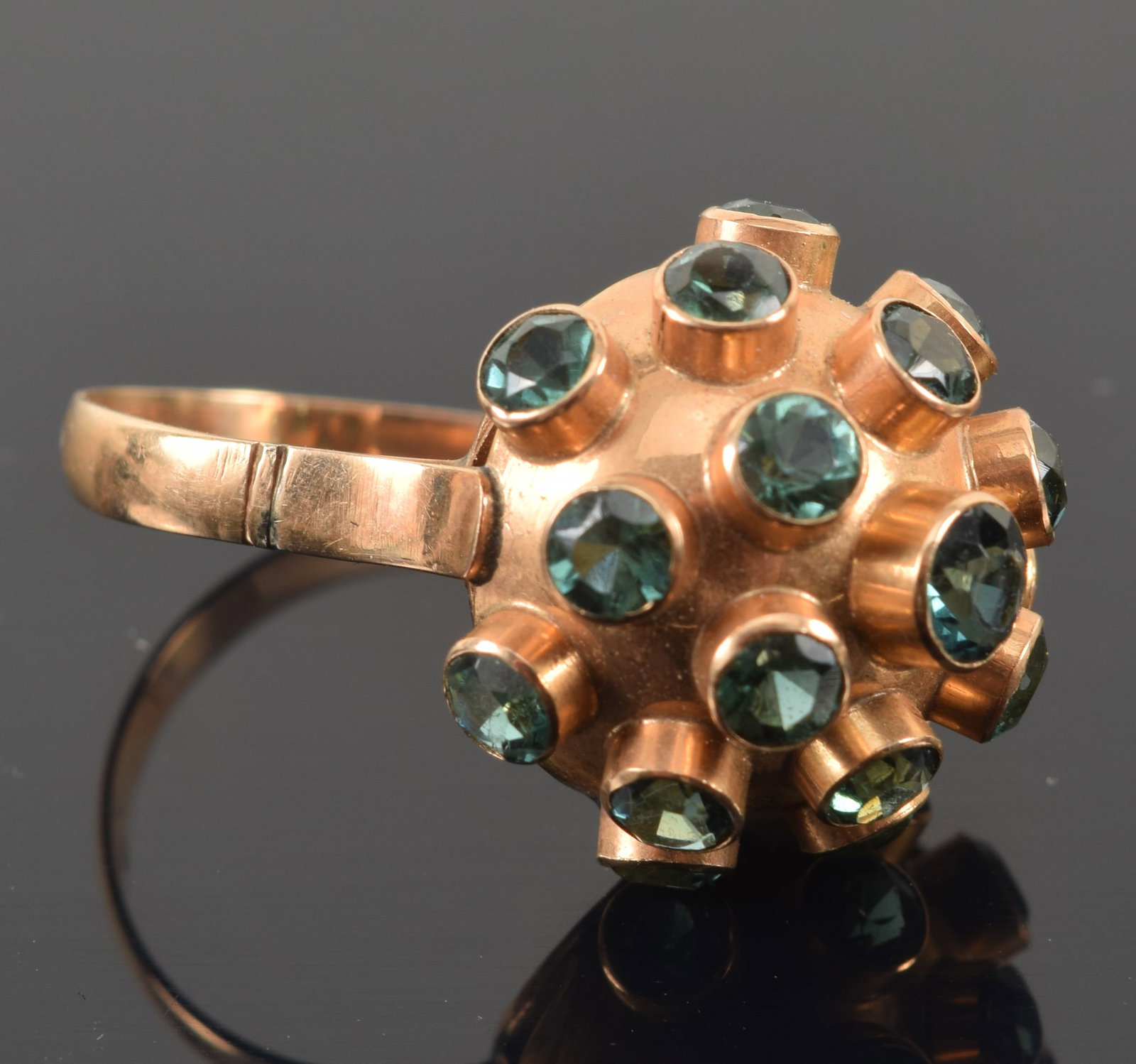 Vintage 18K gold tourmaline mounted sputnik ring. Round cut tourmalines of a green-blue color.: Vintage 18K gold tourmaline mounted sputnik ring. Round cut tourmalines of a green-blue color. Largest at center of top, about 3.6mm diameter. Marked 18K. Ring size 6. 3.8 grams.