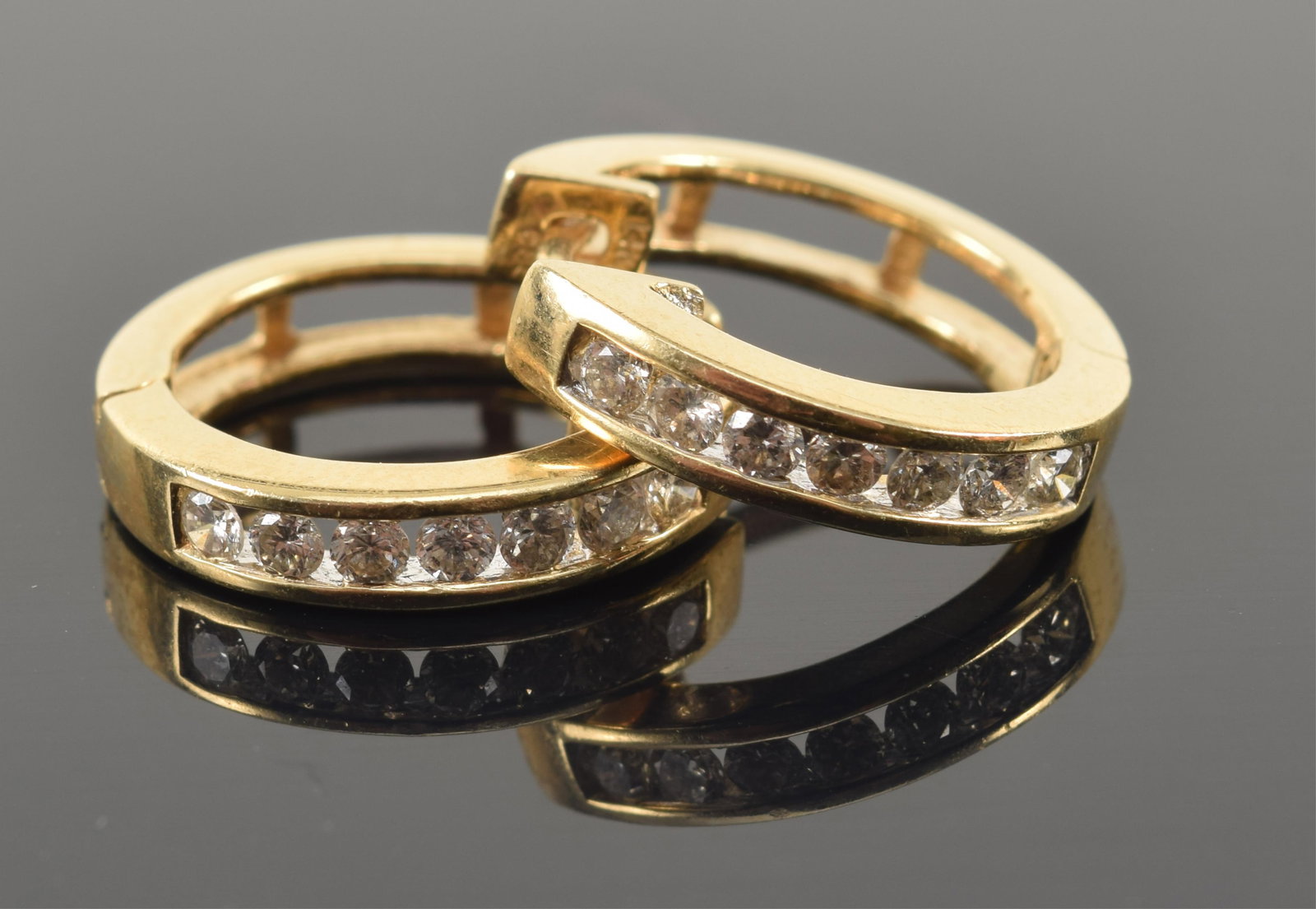 14K gold diamond mounted huggie earrings. Each with 7 round cut diamonds, measuring approx. 2.2mm: 14K gold diamond mounted huggie earrings. Each with 7 round cut diamonds, measuring approx. 2.2mm diameter each. Stamped 14K. 0.75in diameter. 5.7 grams.