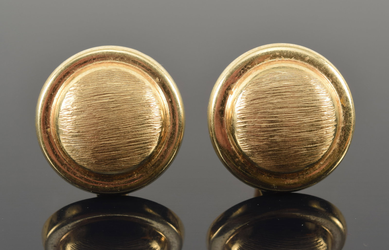 14K gold button form clip earrings. Brushed textured raised surface. Stamped 14K. 0.75in diameter. 9: 14K gold button form clip earrings. Brushed textured raised surface. Stamped 14K. 0.75in diameter. 9 grams.