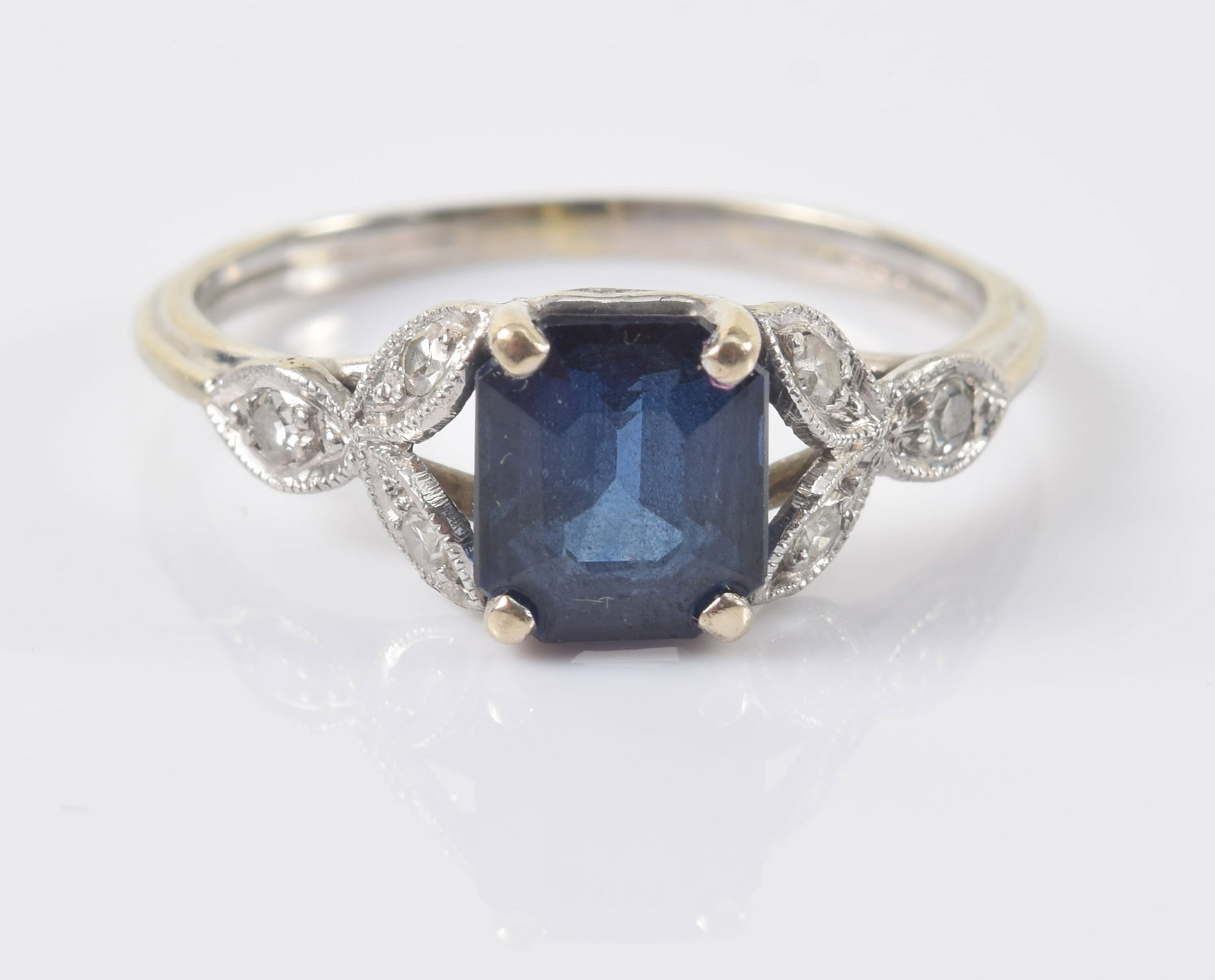 Vintage 14K white gold sapphire and diamond ring. Rectangular cut corner sapphire measures approx.: Vintage 14K white gold sapphire and diamond ring. Rectangular cut corner sapphire measures approx. 6.8 x 5.9mm. Flanked by 3 small diamonds in foliate setting on each side. Unmarked but tests as 14K. 