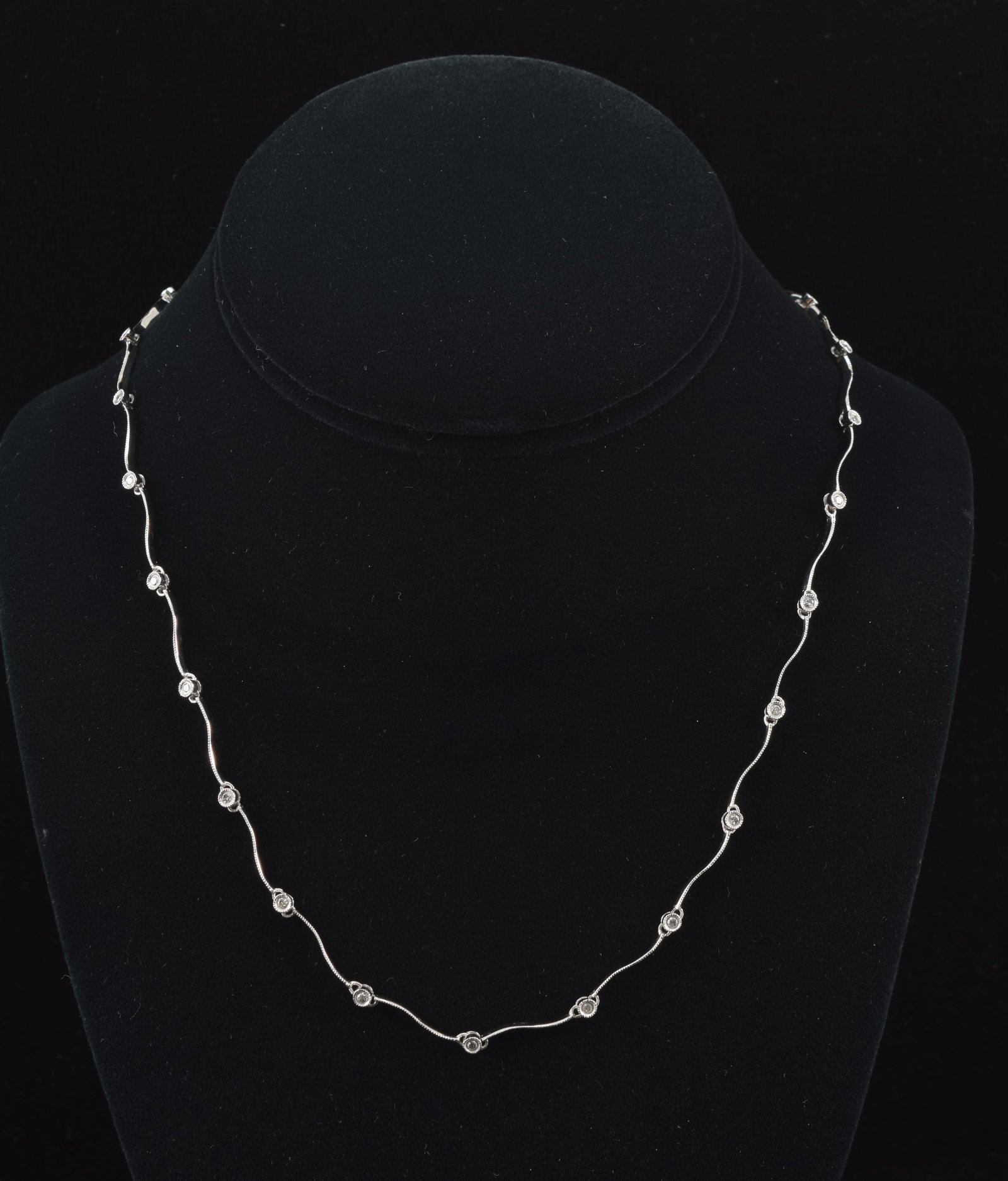 14K white gold wave design diamond necklace. Design of wave form segments with bright cut tops: 14K white gold wave design diamond necklace. Design of wave form segments with bright cut tops alternating with small round cut diamonds, each about 1.8mm diameter. Approx. 0.5ctw. Clasp marked 14K. 1