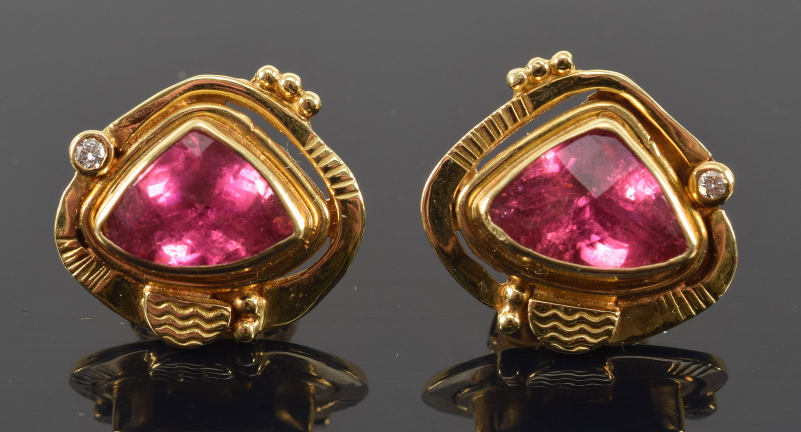 18K gold pink tourmaline modern design earrings. Faceted triangular pink tourmalines measuring about: 18K gold pink tourmaline modern design earrings. Faceted triangular pink tourmalines measuring about 10.8 x 7.8mm. Contoured setting with small round cut diamond accents. Stamped and etched 18K marks,