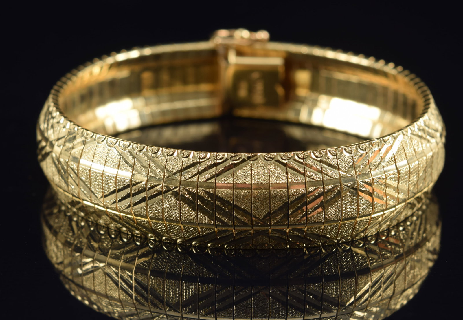 14K gold omega link bracelet with bright cut "X" design. Clasp marked. 7in length. 25.1 grams.: 14K gold omega link bracelet with bright cut "X" design. Clasp marked. 7in length. 25.1 grams.