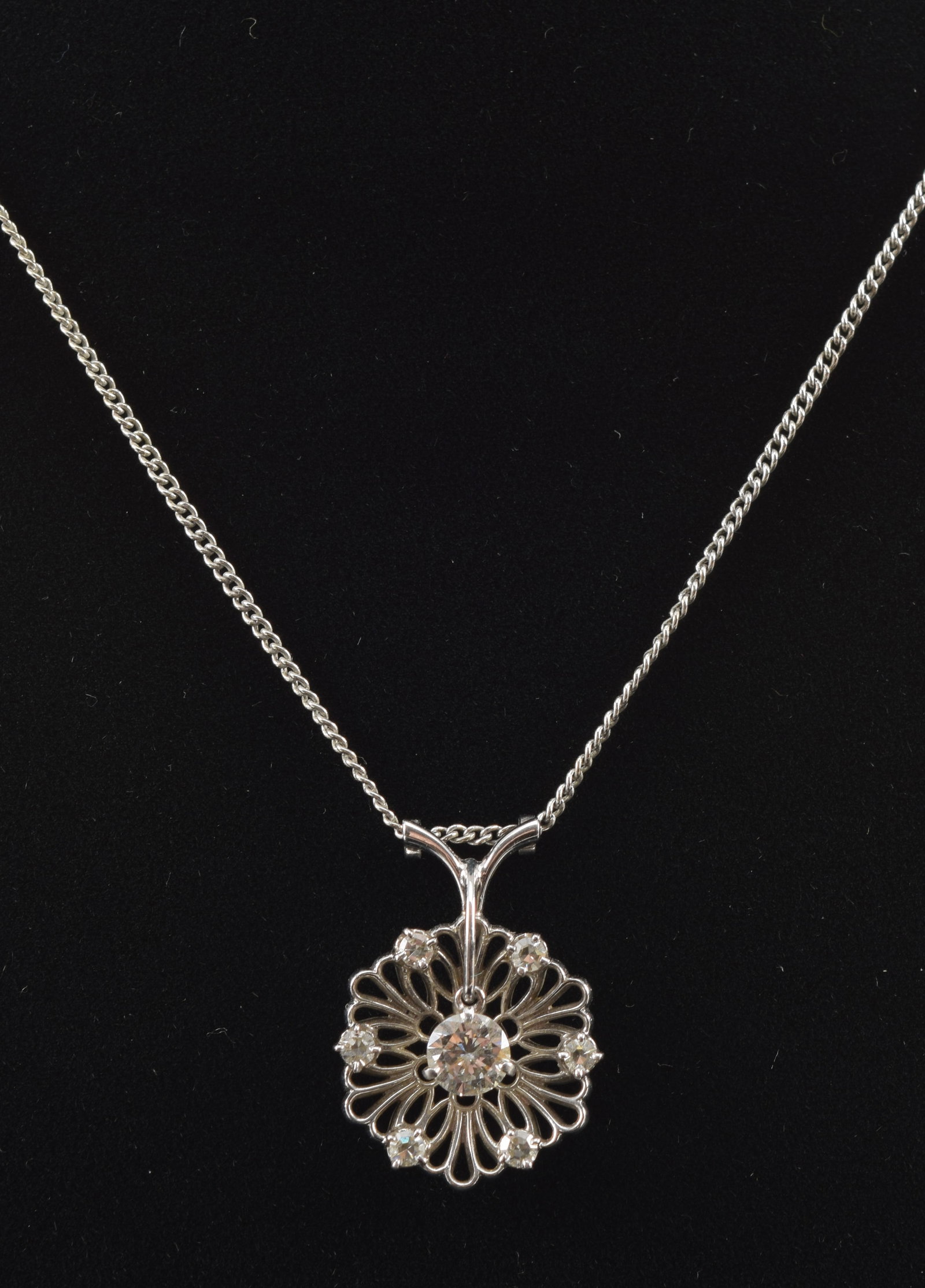 18K white gold diamond floral openwork pendant necklace. Round cut central diamond dangle (5mm: 18K white gold diamond floral openwork pendant necklace. Round cut central diamond dangle (5mm diameter). Marked 18K. Chain 14K. 14in length. 3.9 grams.