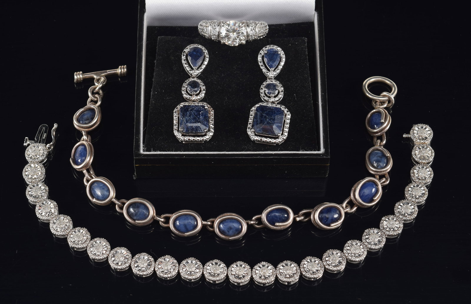 Assortment of sterling silver jewelry. To include: 1) Pair of earrings set with opaque sapphires in: Assortment of sterling silver jewelry. To include: 1) Pair of earrings set with opaque sapphires in square, round and pear shapes. Surrounded by tiny diamonds. 2) Bracelet with oval blue stones. 7in l